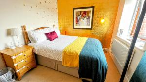 a bedroom with a bed with a colorful blanket and a window at GOLD Penthouse Room 5min to Basingstoke Hospital in Basingstoke