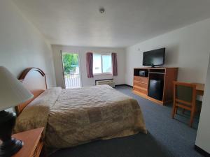 um quarto de hotel com uma cama e uma televisão de ecrã plano em Stellar Motel em Port Orchard