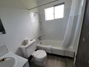 a white bathroom with a toilet and a tub and a sink at Stellar Motel in Port Orchard