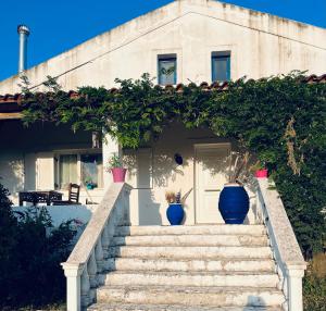 a house with two blue vases on the stairs at Cozy Corfu Bungalow 5 minutes to Aqualand in Corfu