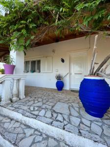 une maison avec deux vases bleus sur une terrasse en pierre dans l'établissement Cozy Corfu Bungalow 5 minutes to Aqualand, à Corfou