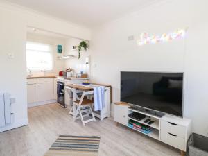 a living room with a large television and a kitchen at Dolly's Lookout in Lowestoft
