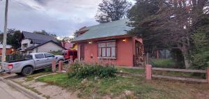 a red house with a truck parked in front of it at CASA DE LA LAGUNA in Ushuaia