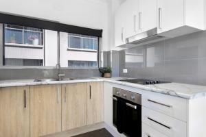 a kitchen with white cabinets and a sink and a stove at Ocean Spray 7 in Coffs Harbour