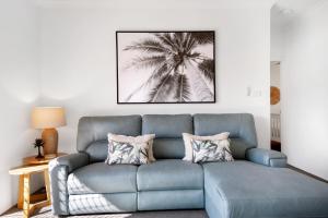 a blue couch in a living room with a palm tree picture at Ocean Spray 7 in Coffs Harbour