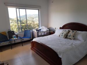 a bedroom with a bed and two chairs and a window at CASA CAMPESTRE COMPLETa in Barbosa