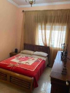 1 dormitorio con 1 cama con manta roja y ventana en Grand appartement 1 chambre en Tánger
