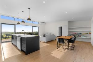a kitchen and living room with a table and chairs at Modern Sanctuary - Waipu Holiday Home in Waipu Cove