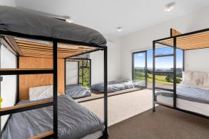two bunk beds in a room with windows at Modern Sanctuary - Waipu Holiday Home in Waipu Cove