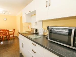 a kitchen with white cabinets and a microwave at Britannia Cottage in Llanrhystyd