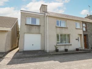 a house with a white garage door on a street at Britannia Cottage in Llanrhystyd