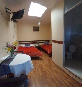 Habitación con 2 camas, mesa y ventana en Hospedaje Balcón Cusqueño, en Cusco