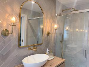 ein Bad mit einem Waschbecken und einer Dusche mit einem Spiegel in der Unterkunft Lujoso apartamento boutique a estrenar con parking gratis in Gijón