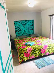 a bedroom with a bed with a colorful bedspread at CHEZ ANIAKI in Nuku Hiva