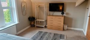 a bedroom with a dresser with a television on it at Homebird Property - Rutland Apartment in Harrogate
