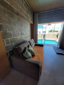 Villa Maré Guaratiba Beach في برادو: غرفة معيشة مع أريكة وجدار من الطوب
