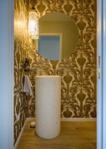 a bathroom with a round mirror and a white column in front of a wall at Downtown Mount Maunganui in Mount Maunganui