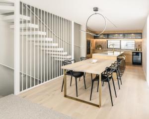 a dining room with a table and chairs and a staircase at Downtown Mount Maunganui in Mount Maunganui