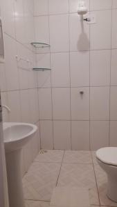 een witte badkamer met een wastafel en een toilet bij Quarto Dani in Jericoacoara