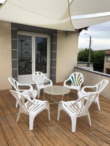 grupa białych krzeseł i stół na tarasie w obiekcie Appartement lumineux avec grande terrasse w mieście Clermont-Ferrand