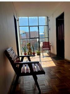 Habitación con banco, mesa y ventana en Hostal Graciela en Oruro