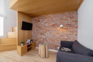 ein Wohnzimmer mit einer Backsteinwand und einer Couch in der Unterkunft Apartment with Mezzanine - Ariańska 14 by Renters in Krakau