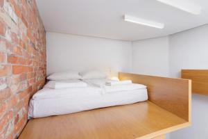 ein Schlafzimmer mit einem Bett an einer Backsteinwand in der Unterkunft Apartment with Mezzanine - Ariańska 14 by Renters in Krakau