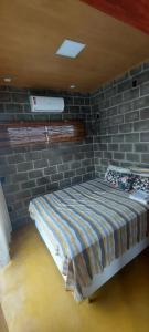 een bed in een kamer met een bakstenen muur bij Villa Maré Guaratiba Beach in Prado