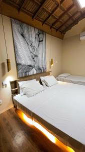 1 dormitorio con 2 camas y un cuadro en la pared en Suítes Naldiane en Imbassai