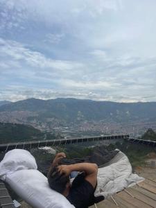 un hombre acostado sobre almohadas en la cima de una montaña en Glamping ecoglam Medellín, en Copacabana