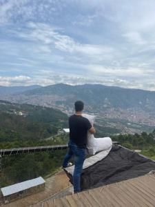 a man standing on the edge of a roof at Glamping ecoglam Medellín in Copacabana
