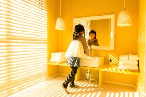 una mujer parada frente a un espejo de baño en 絵本ホテル, en Nara