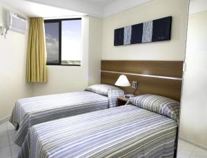 um quarto de hotel com duas camas e uma janela em CJC Short Stay Natal em Natal