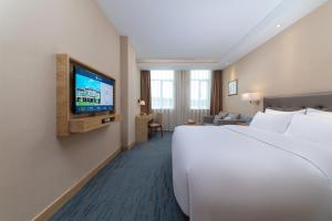 a hotel room with a bed and a flat screen tv at Xiamen Xiang An Yi Hao Hotel in Xiamen