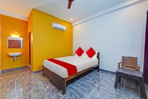 a bedroom with a bed with red pillows and a sink at OYO Flagship Le Gith De Charme with swiming pool in Kottakupam