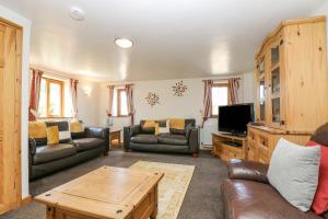 a living room with leather furniture and a flat screen tv at The Wagon Linney in Bude