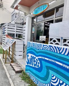 a surf shop with a sign on the side of it at Surfer's Cafe& Hostel in Chatan