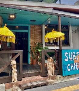 un front de magasin avec deux parapluies devant lui dans l'établissement Surfer's Cafe& Hostel, à Chatan