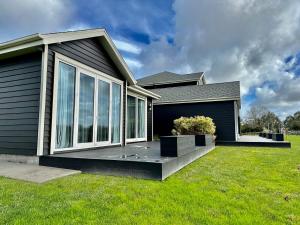 a house with a large window on a lawn at Lifestyle Guesthouse in Dairy Flat