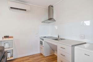 a white kitchen with a sink and a microwave at Swansea Beach Chalets in Swansea