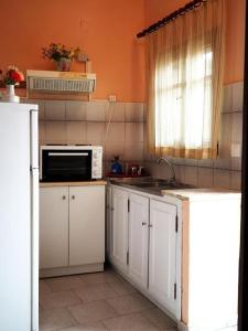 cocina con armarios blancos y microondas en painter's house, en Ágios Ioánnis