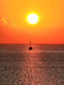 a boat in the ocean with a sunset at Angel Island Eco Resort in Labuan Bajo