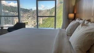 Un dormitorio con una gran cama blanca y una ventana en Apartamento em Frente ao Mar, en Río de Janeiro