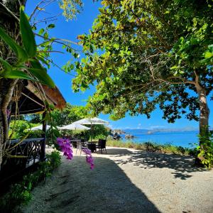 uma praia com mesas e cadeiras e o oceano em Angel Island Eco Resort em Labuan Bajo