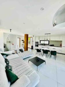 ein weißes Wohnzimmer mit einer Couch und einem Tisch in der Unterkunft Villa Neuve Piscine Privée La Ciotat in La Ciotat