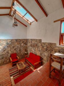 Habitación con 2 sillas rojas y pared de piedra. en Ecolodge K'arasirca en Comunidad Yumani