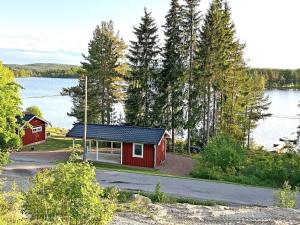 a red cabin with a view of a lake at Holiday home ENVIKEN in Svärdsjö