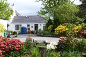 a white house with flowers in front of it at Achnamara Apartment in Connel