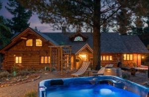 una casa di tronchi con una vasca idromassaggio di fronte di Fairytale Log Cabin - Homewood Forest Retreat ad Alexandra