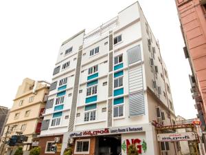 um edifício branco com janelas azuis numa rua em Capital O Sri Navya Grand Near Nexus Hyderabad em Lingampalli